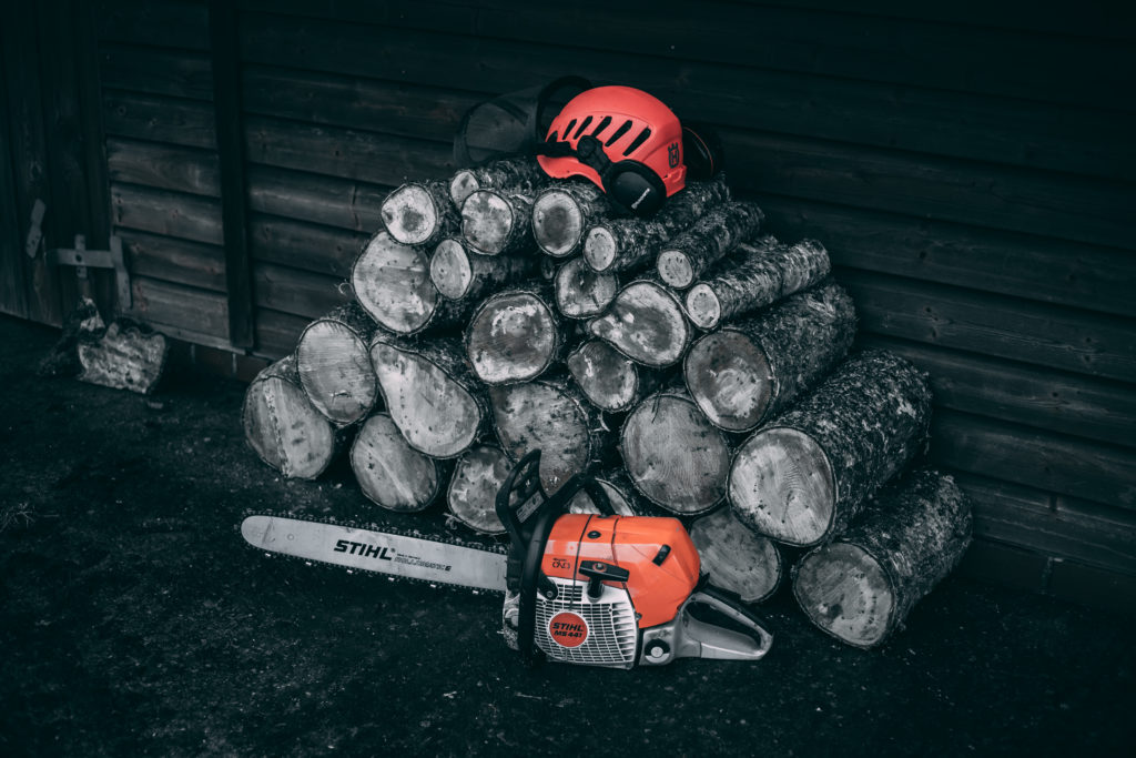 Log pile with chainsaw and safety helmet