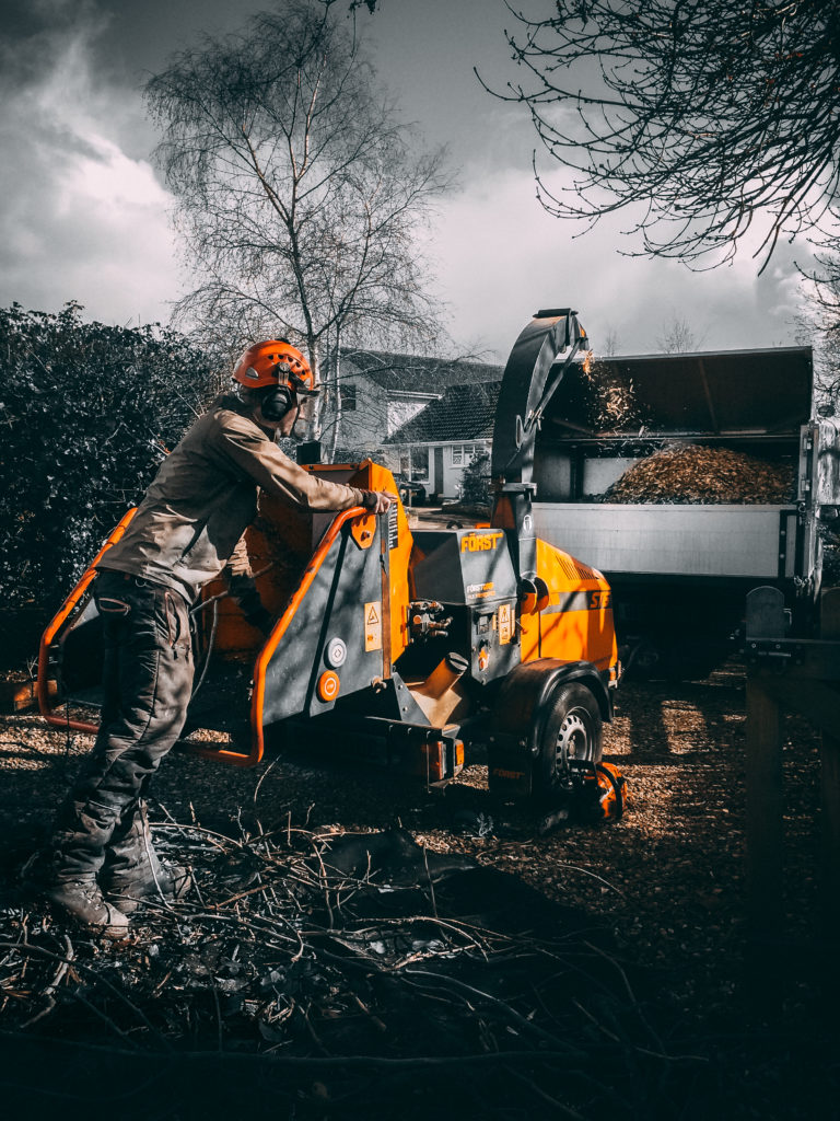 Photo of an arborist using a branch chipper